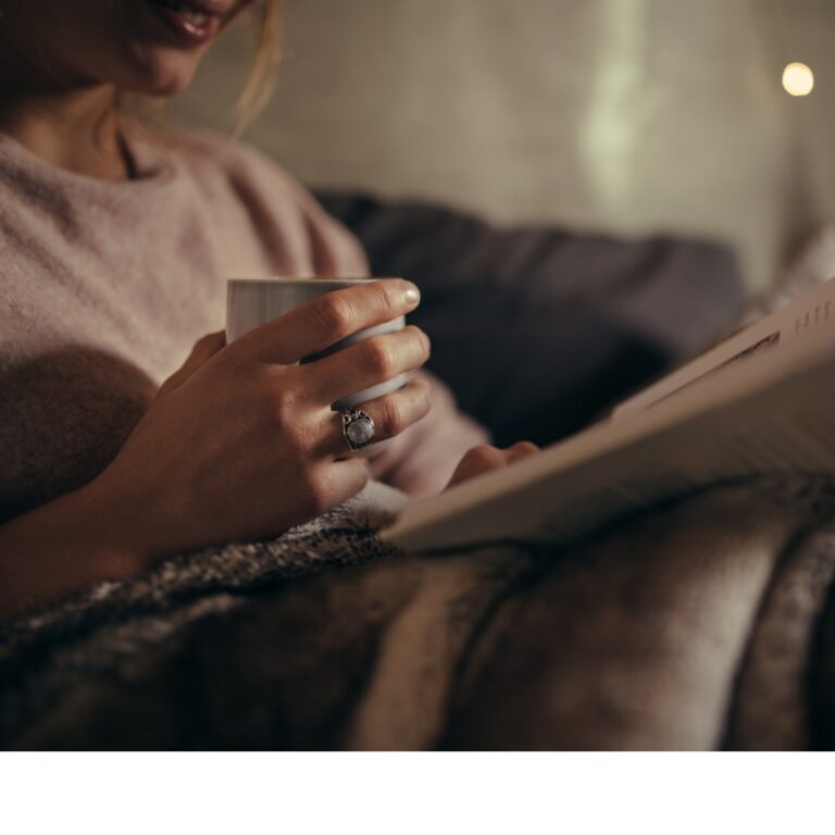 A warm mug and journal on a coffee table in a cosy evening setting