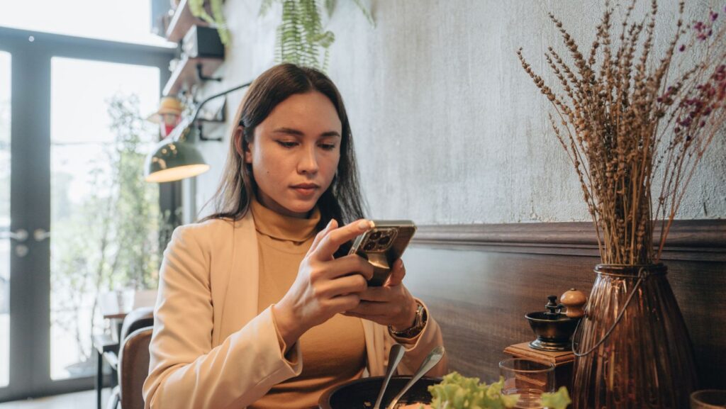 Woman looking at phone with concern after eating