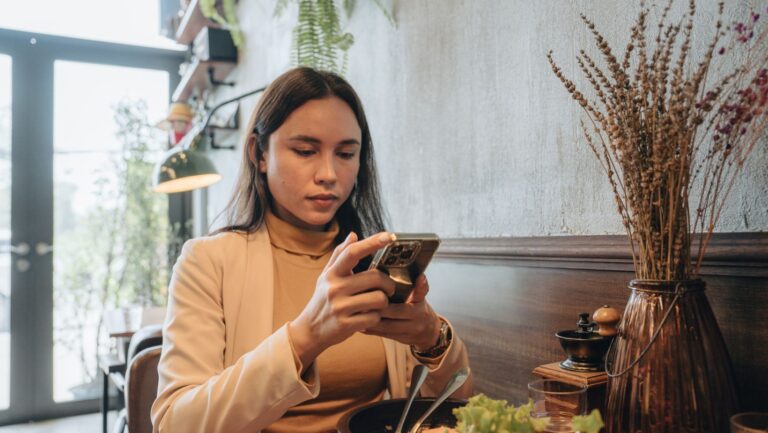 Woman looking at phone with concern after eating