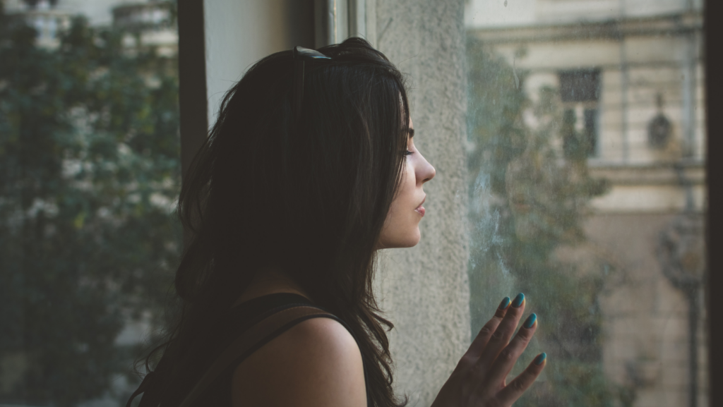 Blog 3 Woman pausing to reflect by a window, soft natural light